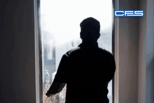 A silhouette of a professional cleaner applies a solution to a large window using a squeegee, with the CFS (Commercial Film Specialists) logo in the top right corner, highlighting expert tint care in a residential setting.