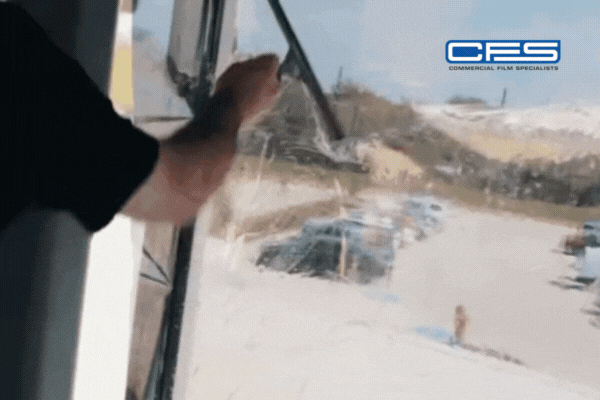 GIF showing a professional installer applying a sheet of window film to a large glass window, smoothing it out to remove air bubbles. The CFS (Commercial Film Specialists) logo appears in the corner, reinforcing brand identity and trust.