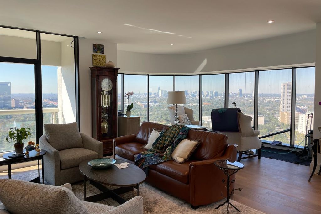 Modern high-rise living room with floor-to-ceiling windows offering a panoramic city view, equipped with heat-reducing window film that subtly darkens the glass to block solar heat while preserving natural light.