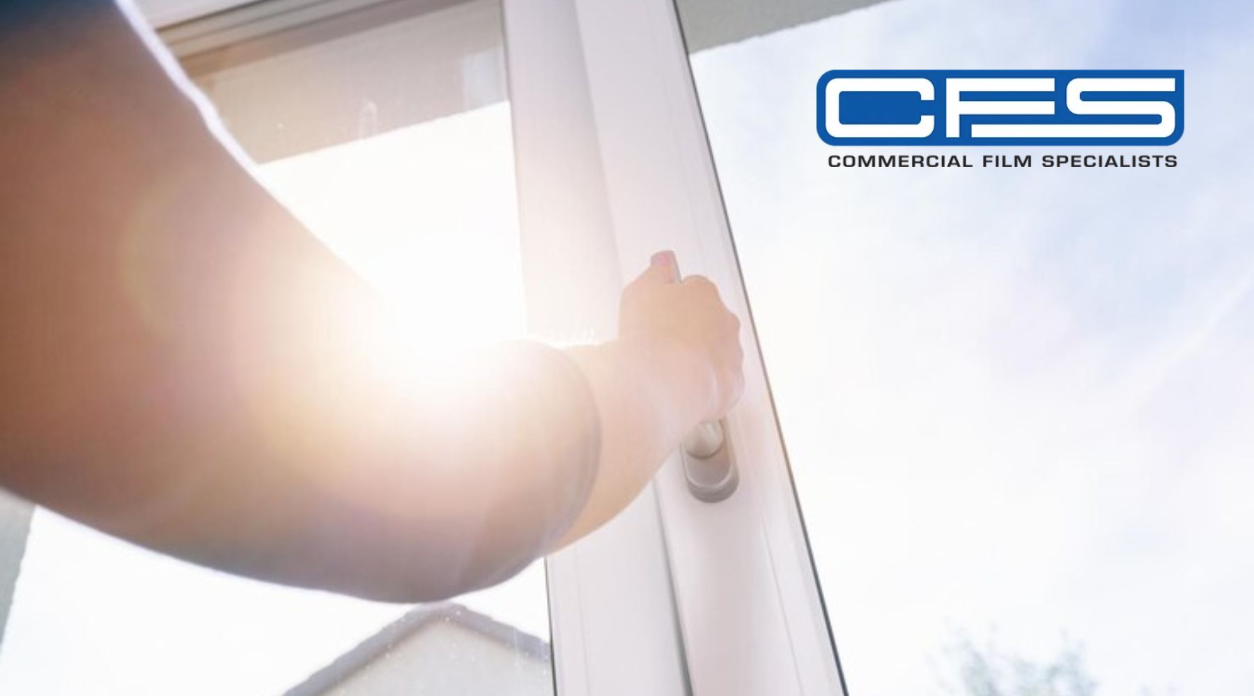 Person opening a glass door with bright sunlight streaming through, symbolizing the effectiveness of window film in blocking heat and glare. The logo “CFS Commercial Film Specialists” appears in the top right corner.