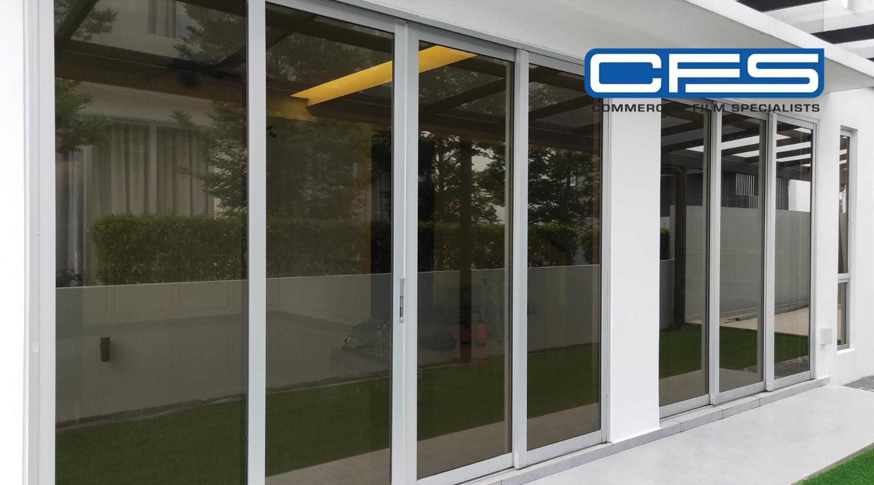 Tinted sliding glass doors on a modern home exterior, installed by Commercial Film Specialists to reduce glare and enhance privacy.