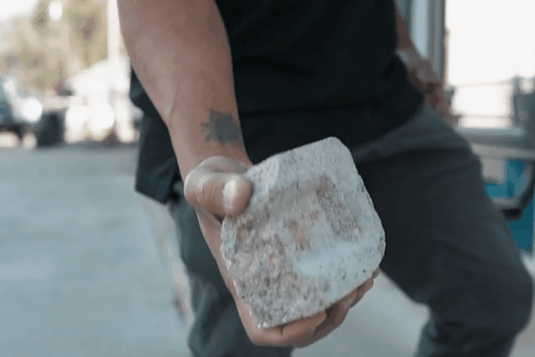 Person striking a window with security film applied, showing the glass remains intact despite shattering.