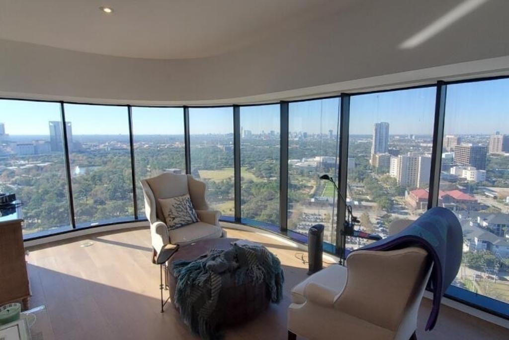 High-rise residential living room with full-height tinted windows offering panoramic views of the Houston skyline while reducing glare and heat.