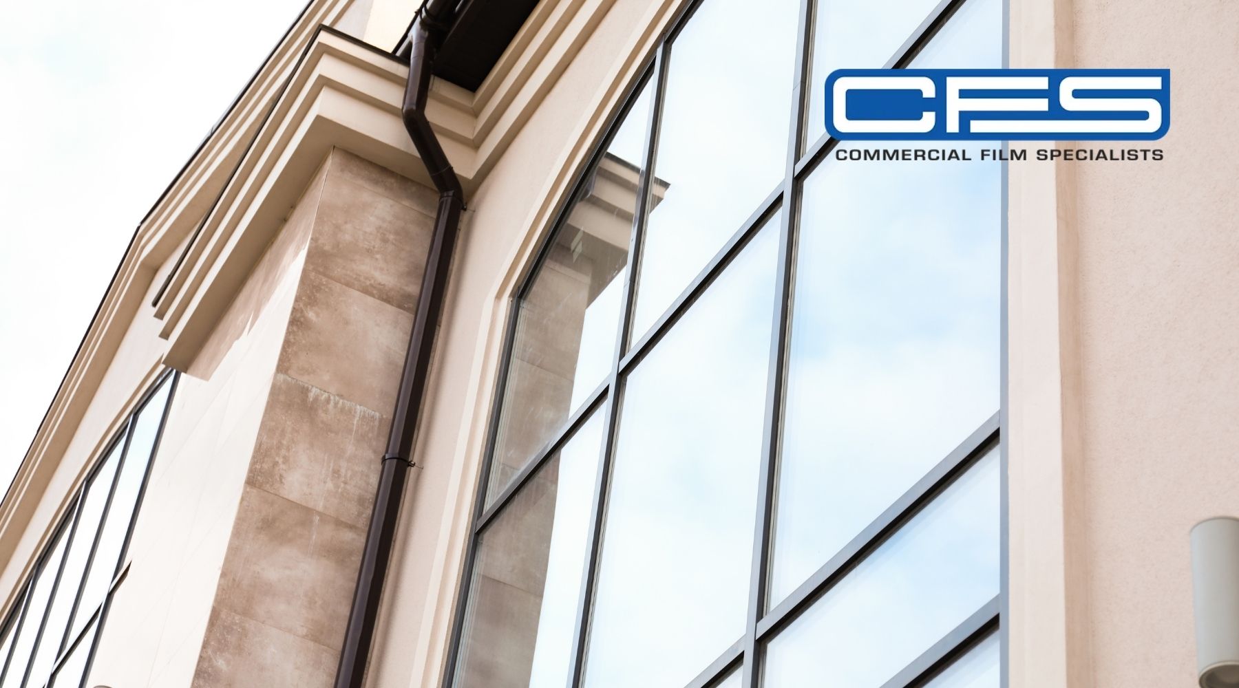 Modern commercial building exterior with large glass windows and Commercial Film Specialists logo